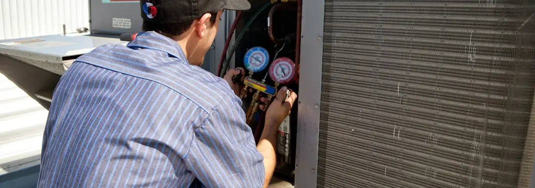HVAC technician servicing a condenser unit in Camp Springs