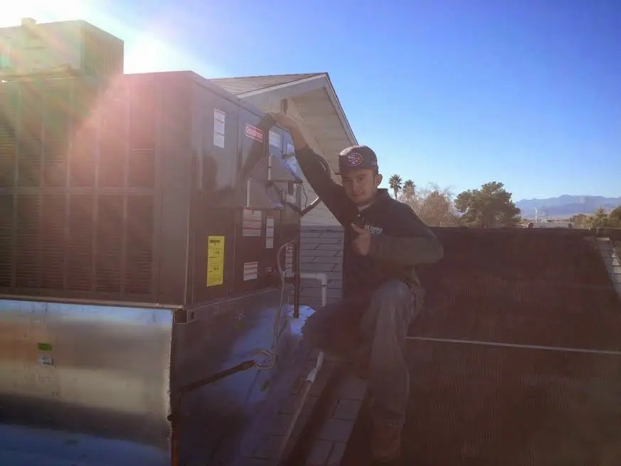 HVAC technician performing Air Duct Cleaning on a rooftop unit in Camp Springs